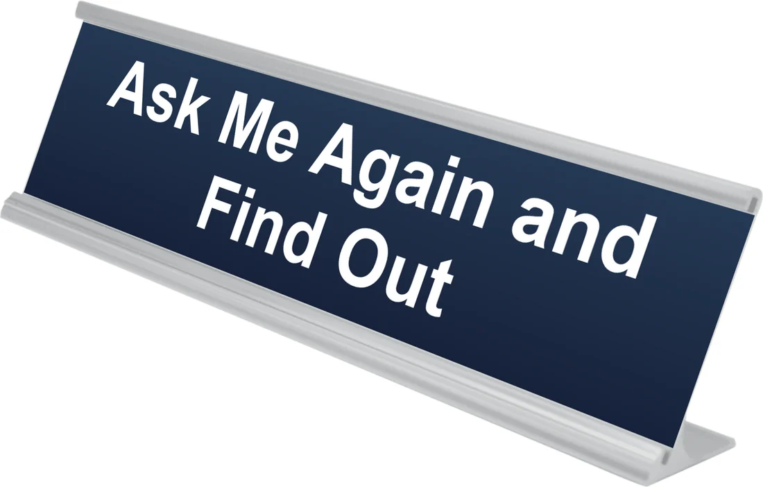 Ask Me Again and Find Out desk plate in navy, shown in an aluminum desk holder