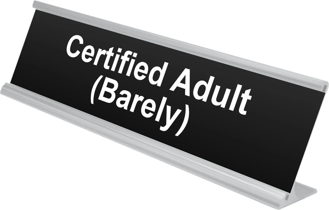 Certified Adult (Barely) desk plate in black, shown in an aluminum desk holder