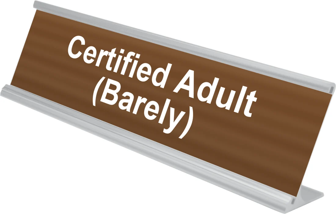 Certified Adult (Barely) desk plate in walnut, shown in an aluminum desk holder