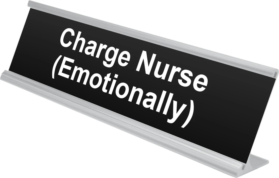 Charge Nurse (Emotionally) desk plate in black, shown in an aluminum desk holder