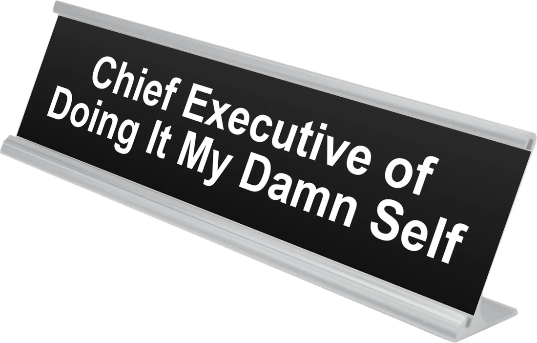 Chief Executive of Doing It My Damn Self desk plate in black, shown in an aluminum desk holder