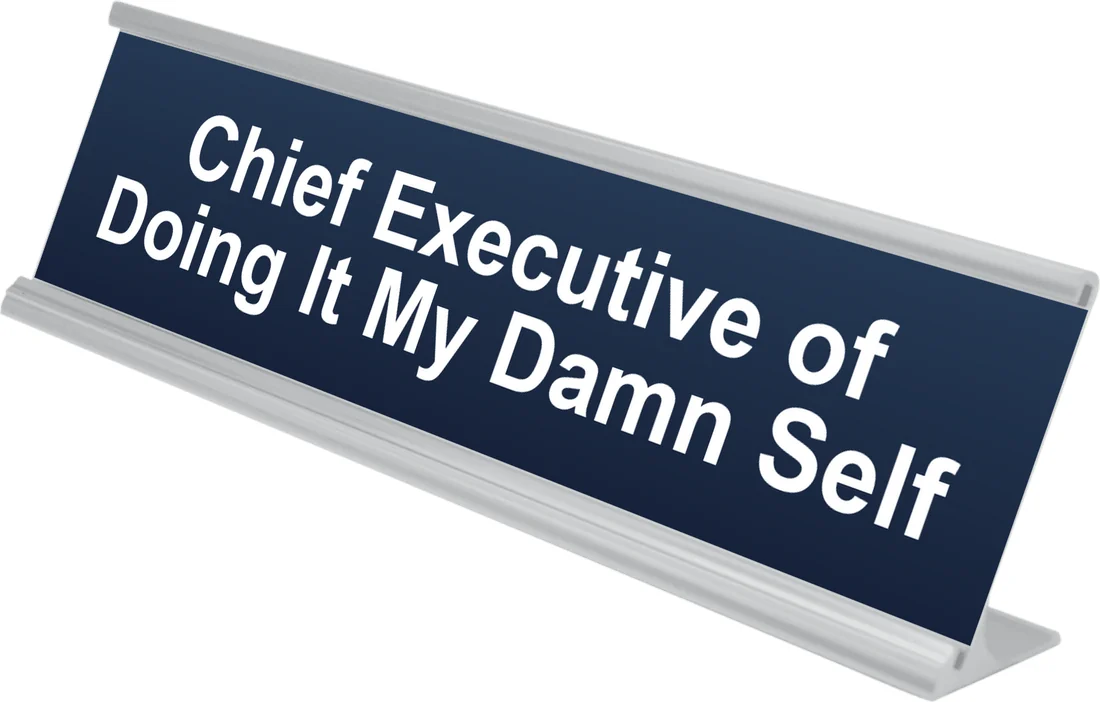 Chief Executive of Doing It My Damn Self desk plate in navy, shown in an aluminum desk holder