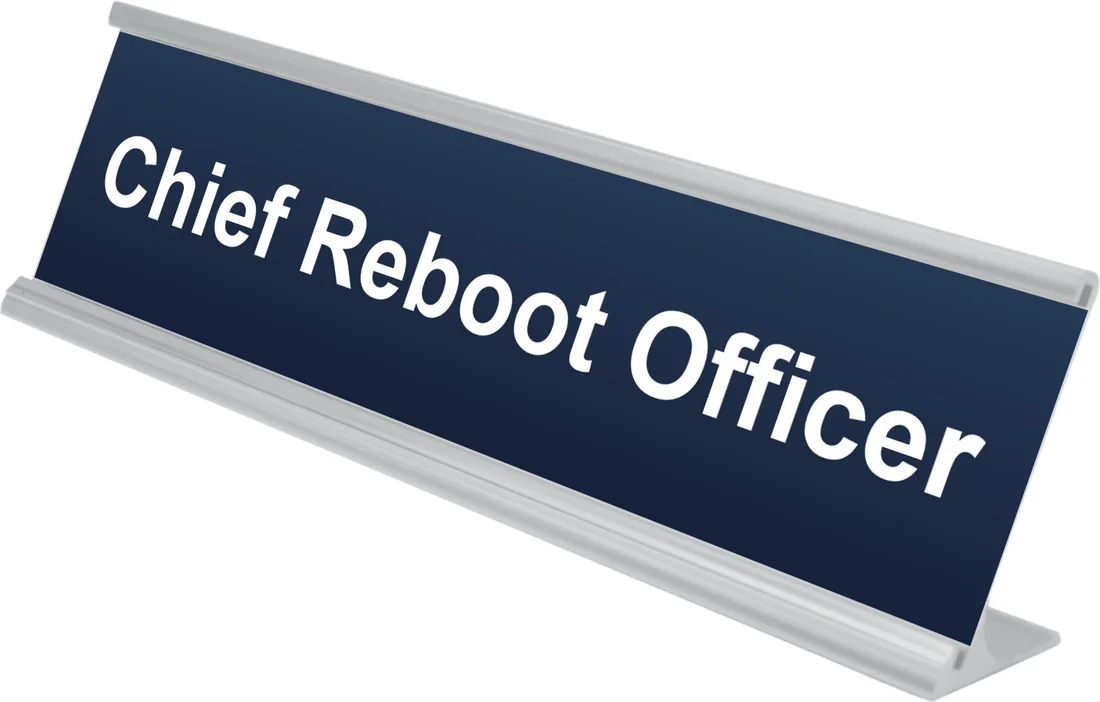 Chief Reboot Officer desk plate in navy, shown in an aluminum desk holder
