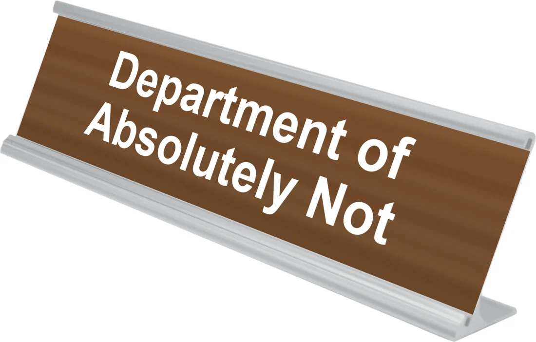 Department of Absolutely Not desk plate in walnut, shown in an aluminum desk holder