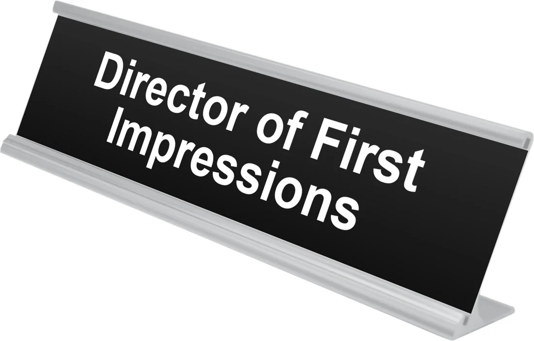 Director of First Impressions desk plate in black, shown in an aluminum desk holder