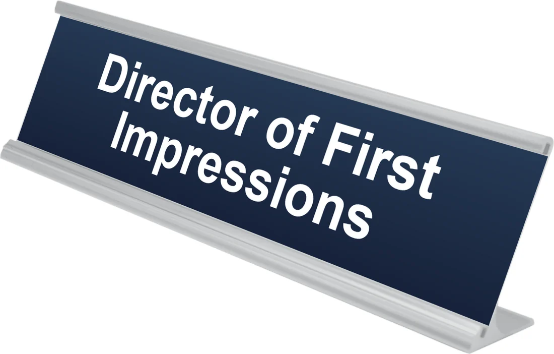 Director of First Impressions desk plate in navy, shown in an aluminum desk holder