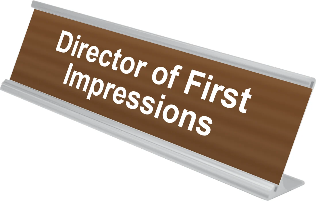 Director of First Impressions desk plate in walnut, shown in an aluminum desk holder