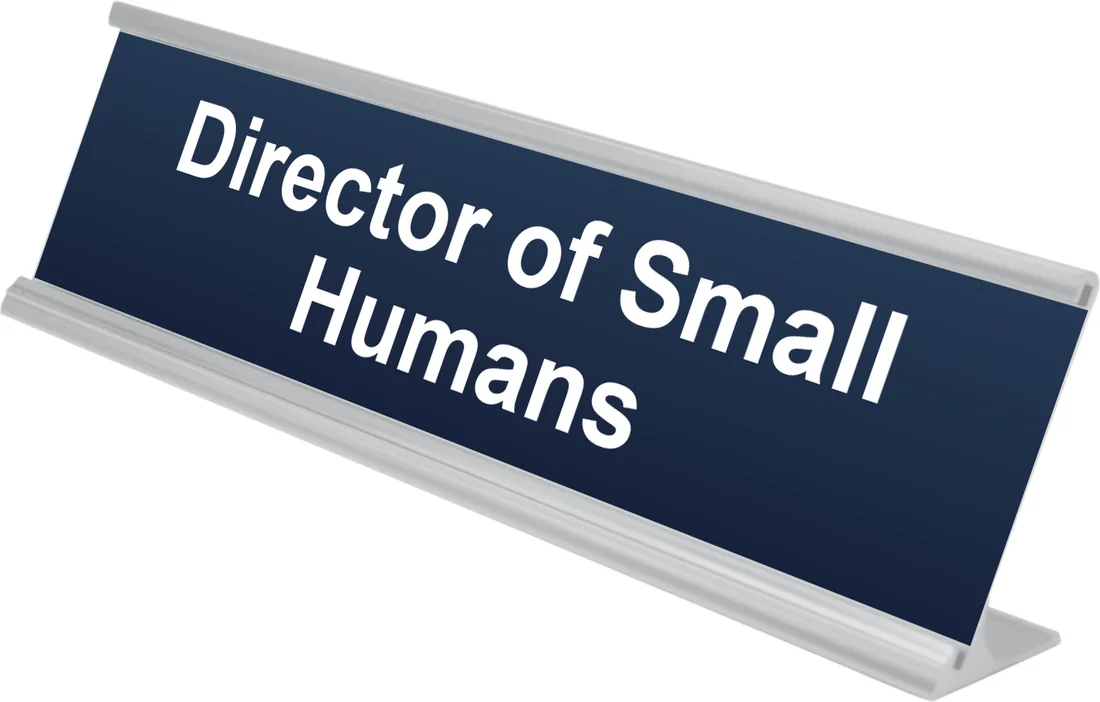 Director of Small Humans desk plate in navy, shown in an aluminum desk holder