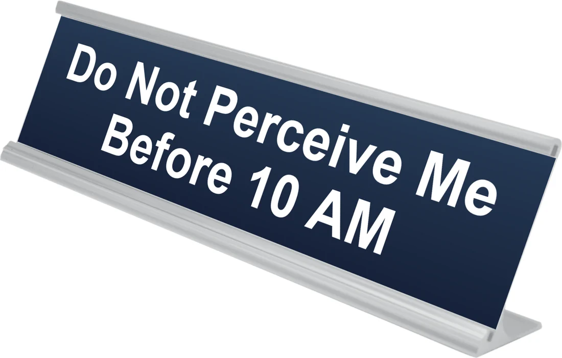 Do Not Perceive Me Before 10 AM desk plate in navy, shown in an aluminum desk holder