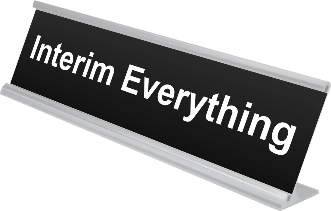 Interim Everything desk plate in black, shown in an aluminum desk holder