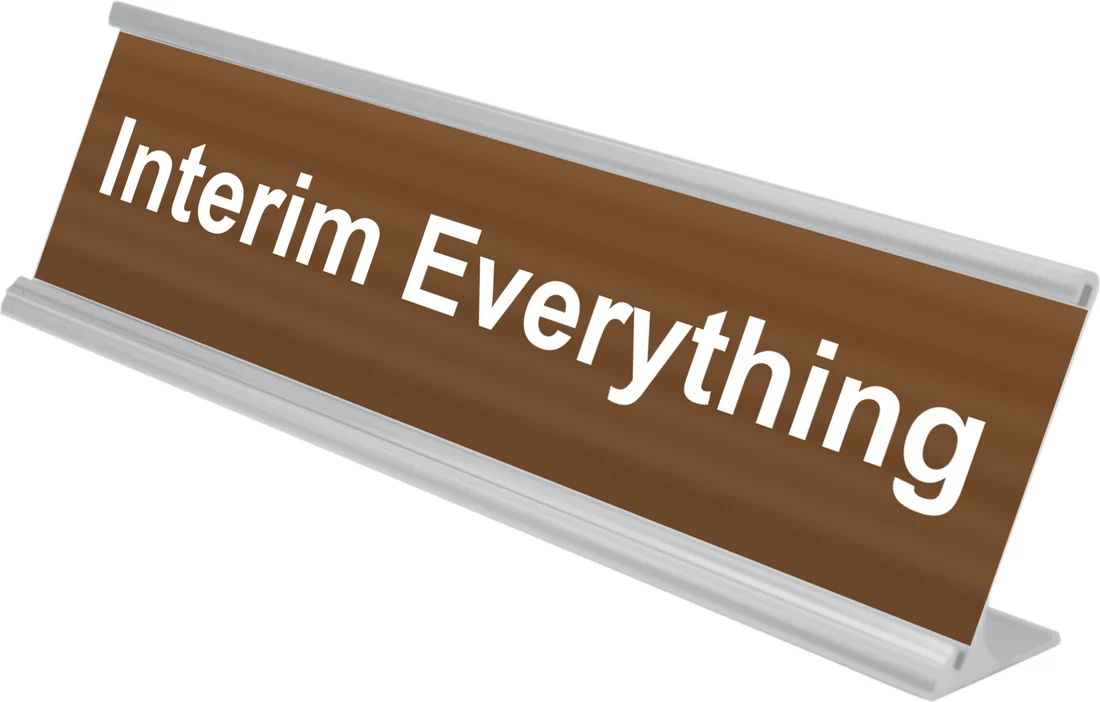 Interim Everything desk plate in walnut, shown in an aluminum desk holder
