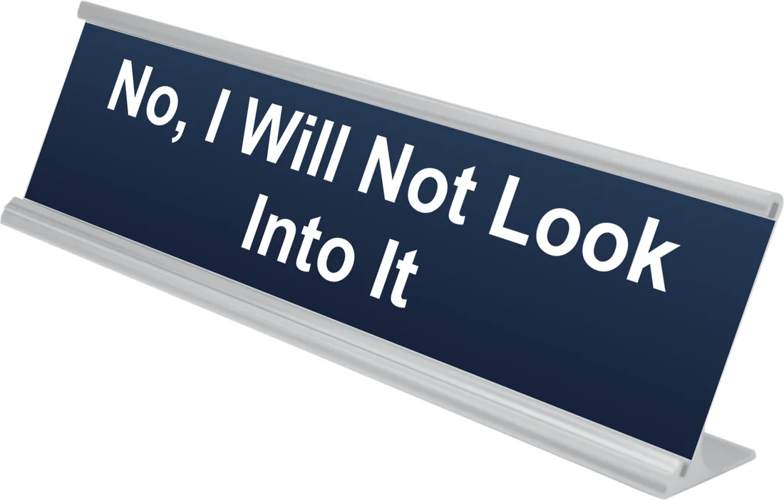 No, I Will Not Look Into It desk plate in navy, shown in an aluminum desk holder