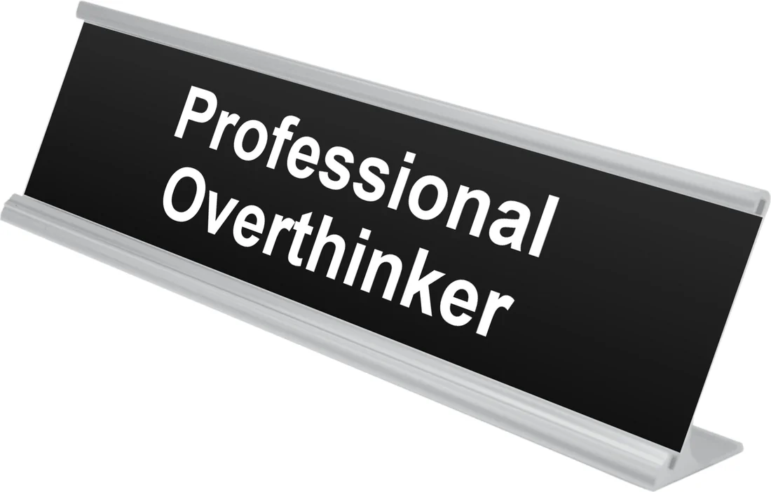 Professional Overthinker desk plate in black, shown in an aluminum desk holder