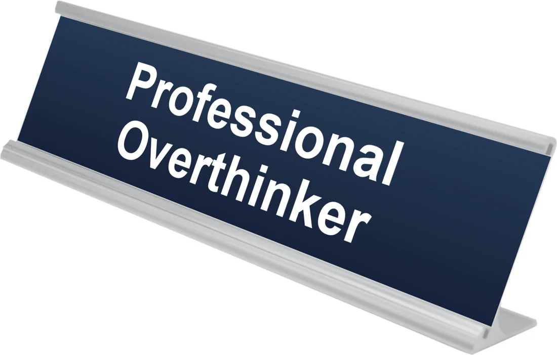 Professional Overthinker desk plate in navy, shown in an aluminum desk holder