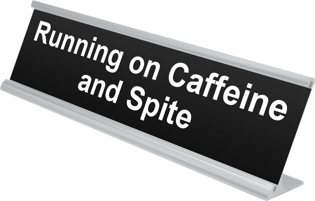Running on Caffeine and Spite desk plate in black, shown in an aluminum desk holder