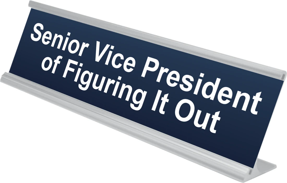 Senior Vice President of Figuring It Out desk plate in navy, shown in an aluminum desk holder