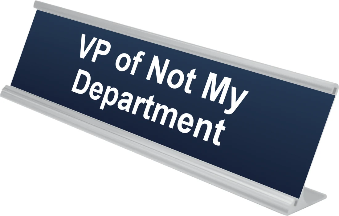 VP of Not My Department desk plate in navy, shown in an aluminum desk holder